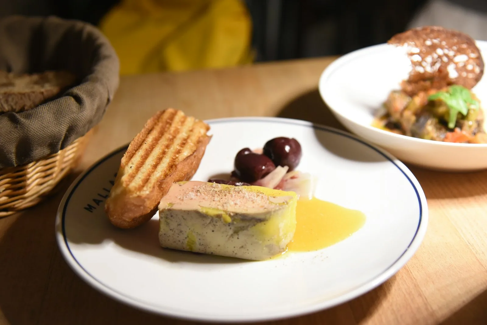 Foie gras dressé sur une assiette avec pain grillé et olives, présentation gastronomique soignée