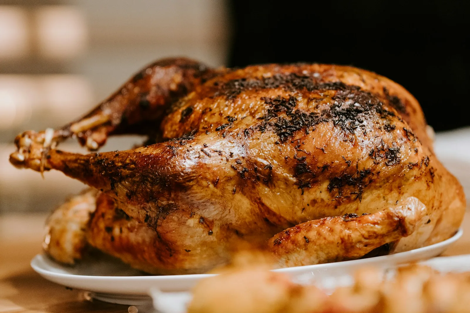 Volaille rôtie entière posée sur une assiette en céramique blanche, lumière douce et sobre